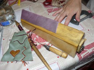 It is mounted on the workbench. The leather strap is the same as in the full size model. The pressure provided in this case by foot only.